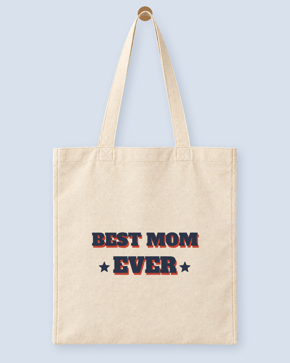 Natural canvas tote printed with “BEST MOM EVER”, hanging on a wooden peg.