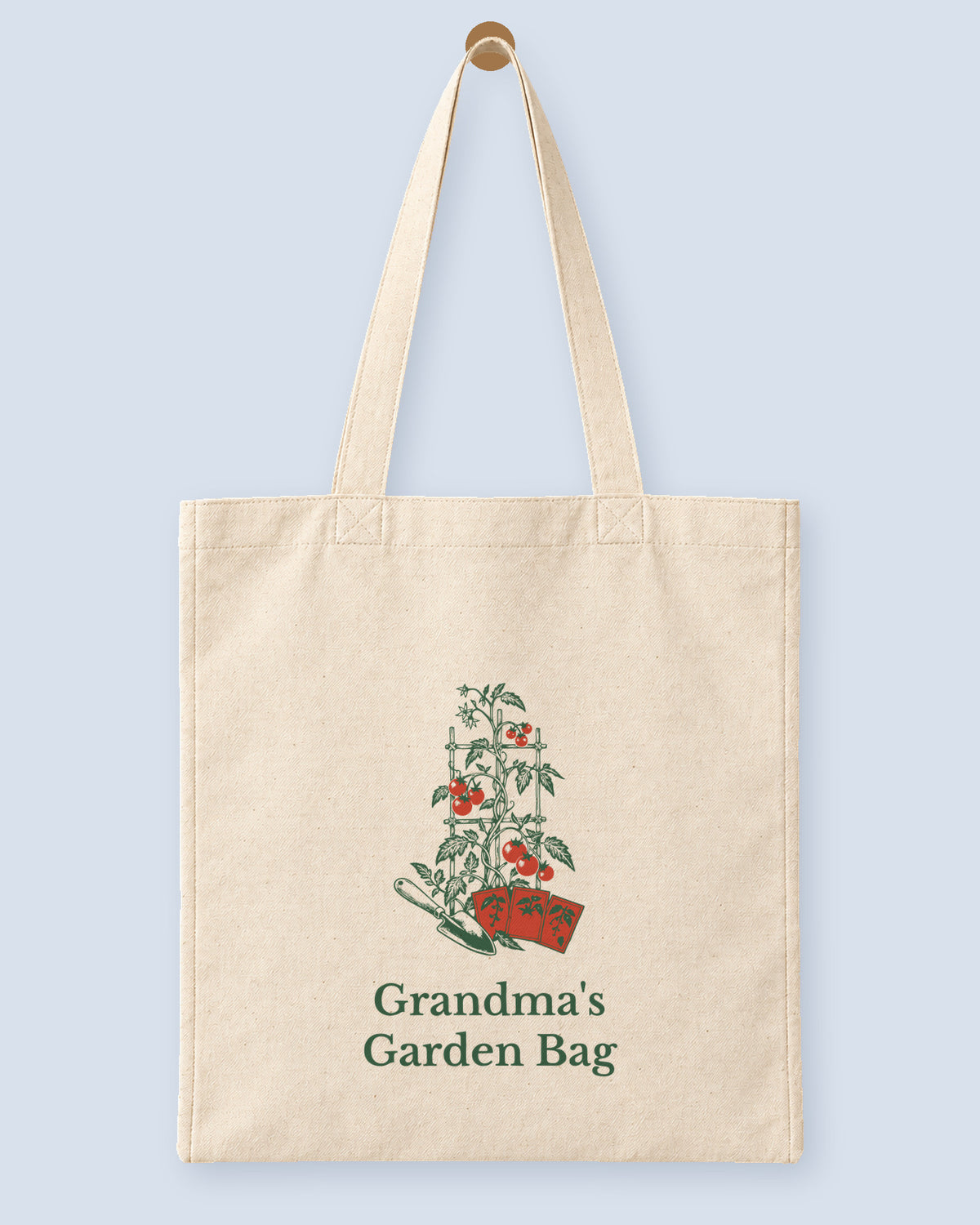 Natural canvas tote printed with “Grandma's Garden Bag”, hanging on a wooden peg.