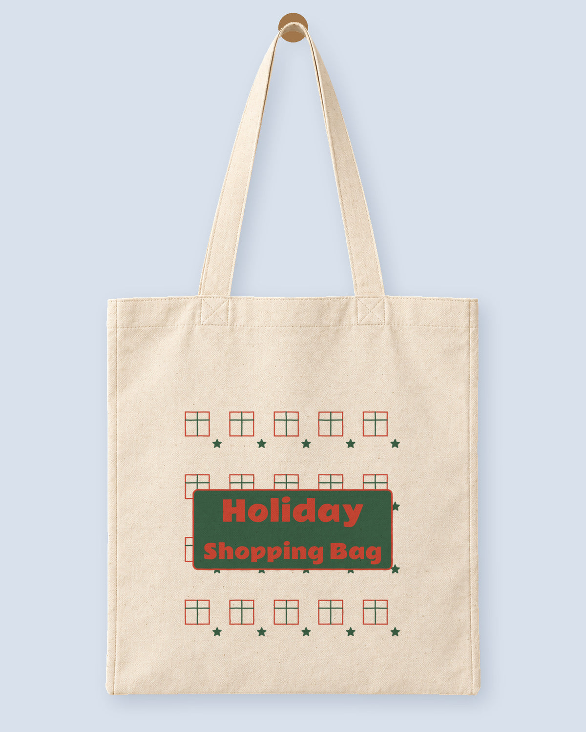 Natural canvas tote printed with “Holiday Shopping Bag”, hanging on a wooden peg.