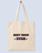 Natural canvas tote printed with “BEST MOM EVER”, hanging on a wooden peg.