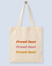 Natural canvas tote printed with “Proud Aunt”, hanging on a wooden peg.