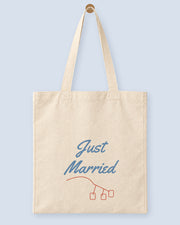 Natural canvas tote printed with “Just Married”, hanging on a wooden peg.