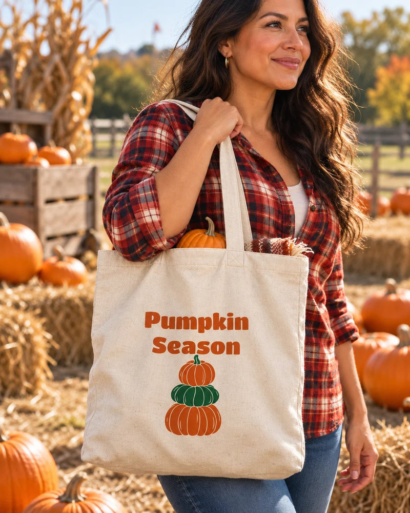 Latina woman carrying a natural canvas tote printed with “Pumpkin Season” in orange, forest. Styled digital image.