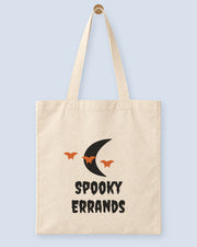 Natural canvas tote printed with “Spooky Errands”, hanging on a wooden peg.
