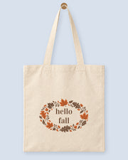 Natural canvas tote printed with “hello fall”, hanging on a wooden peg.