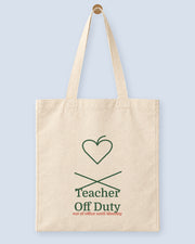 Natural canvas tote printed with “Teacher Off Duty”, hanging on a wooden peg.