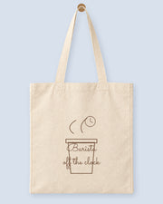 Natural canvas tote printed with “Barista off the clock”, hanging on a wooden peg.
