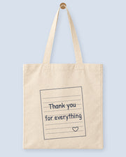 Natural canvas tote printed with “Thank you for everything”, hanging on a wooden peg.