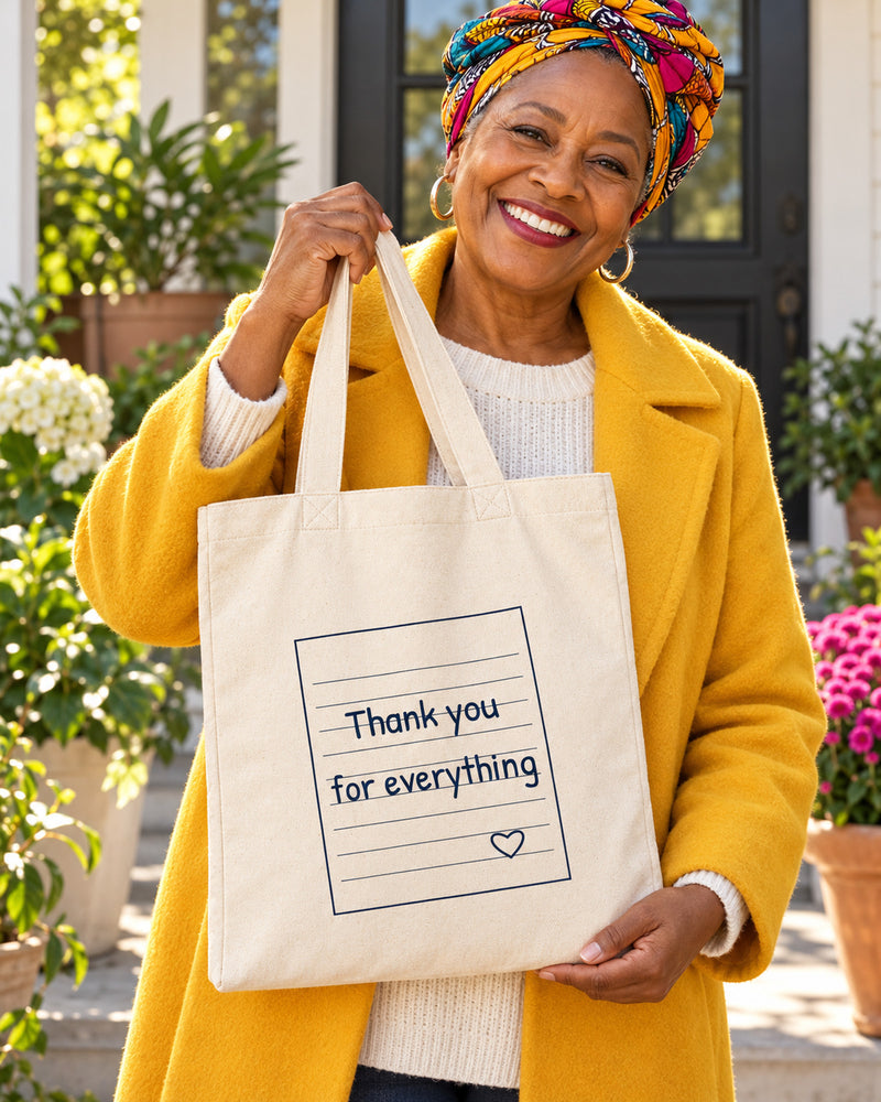 Black woman carrying a natural canvas tote printed with “Thank you for everything” in navy. Styled digital image.
