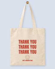 Natural canvas tote printed with “THANK YOU”, hanging on a wooden peg.